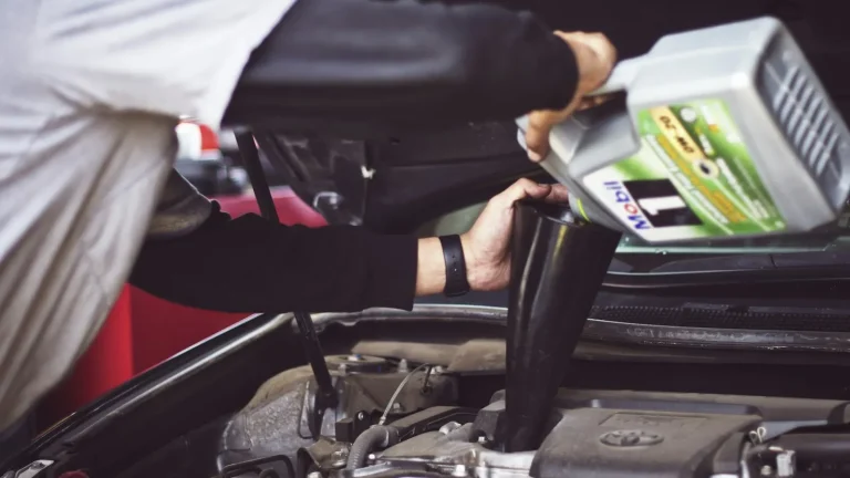 Mechanic topping up engine oil during a service